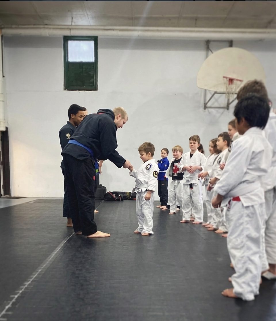 A coach greeting a line of young students at the start of class